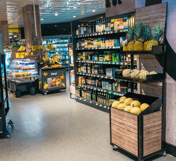 Deuxième point de vente avec trois étagères et un présentoir en bois. Chaque étagère présente de manière attrayante différents fruits, comme par exemple des melons.