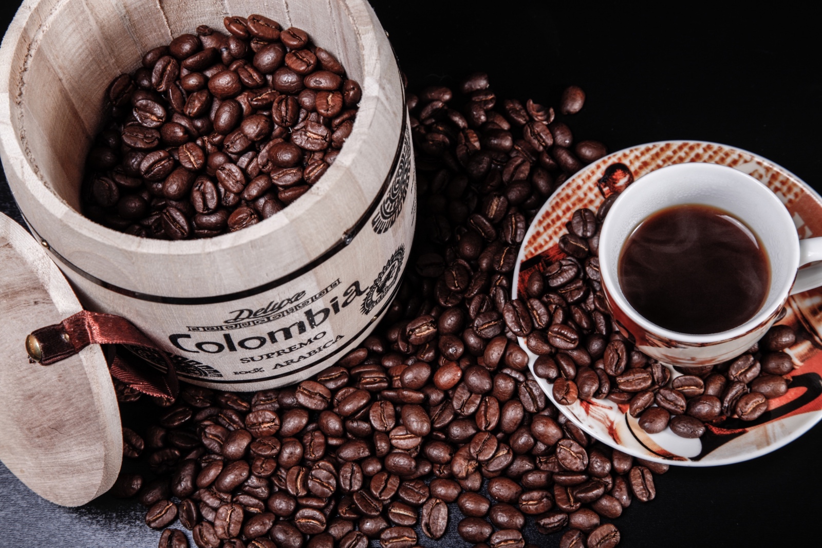 Image d'un tonneau de grains de café, à côté d'une tasse de café